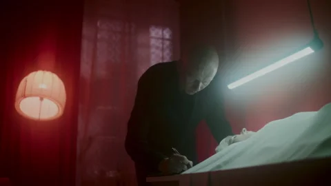 A man looking at the corpse on the table under the blue light 스톡 동영상 259851158