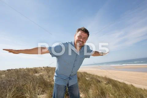 Man looking into distance with hands up against the sea Stock Photos