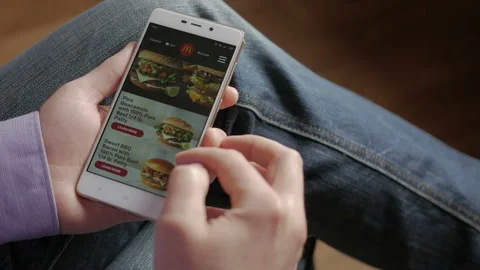 Man looking for diverse menu and mccafe in the McDonalds app before ordering  Stock Footage 87310981