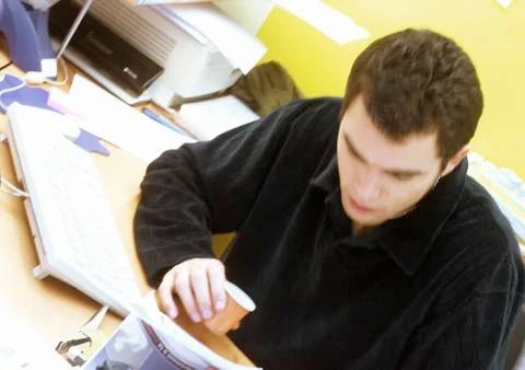 Man looking down, having a coffee at desk Foto stock