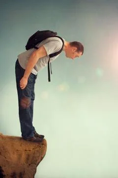 Man looking down from a rocky ledge Stock Photos