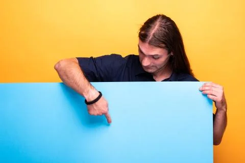 Man looking down while pointing at cardboard banner Stock Photos