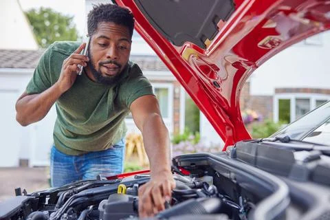 Man Looking At Engine After Car Breakdown Calling Auto Recovery On Mobile Pho 스톡 사진