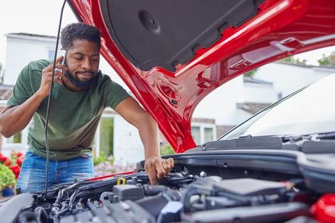 Man Looking At Engine After Car Breakdown Calling Auto Recovery On Mobile Pho Stock Photos