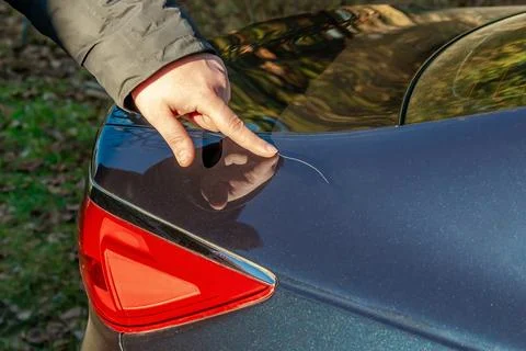 Man looking examining scratch on his car trunk.Unexpectable vehicle damage Foto stock