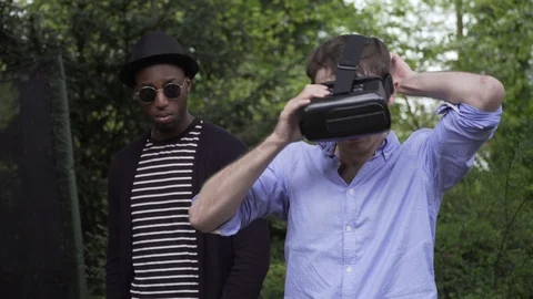Man looking at friend curious VR headset Stock Footage 89922191
