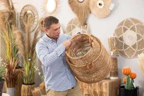Man looking for functional spacious wicker baskets at store Stockfoto's