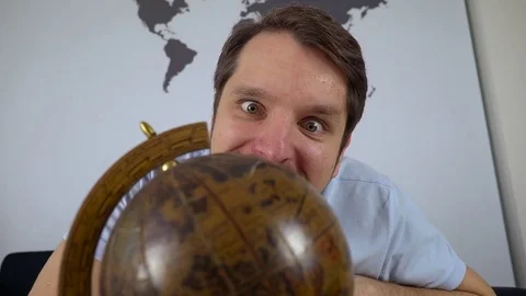 Man looking at globe and picking travel destination at home on the couch Видео 74862945