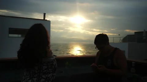A man looking at his cell phone while his partner watches a beautiful sunset Stock Footage 178472228
