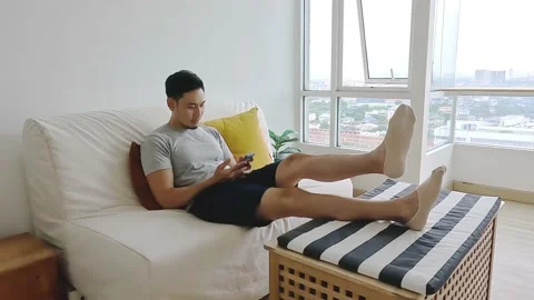 Man looking at his mobile while relax on sofa in his living room. Stock Footage 200873064