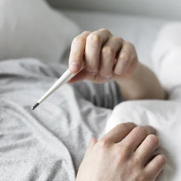 Man looking at his temperature on a thermometer Stock Photos