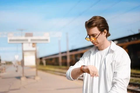 Man looking at his watch while waiting on a train station platform. A passe.. 스톡 사진