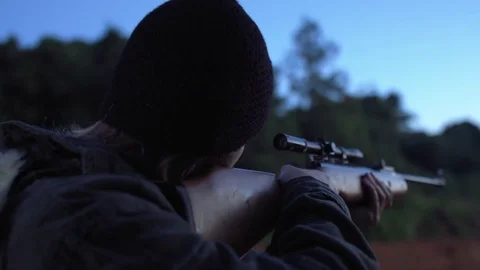 Man looking to the horizon and aiming a gun in a forest. Stock Footage 76473448