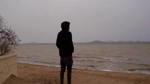 Man looking the horizon of the beach in a bad day Stock Footage 148501123