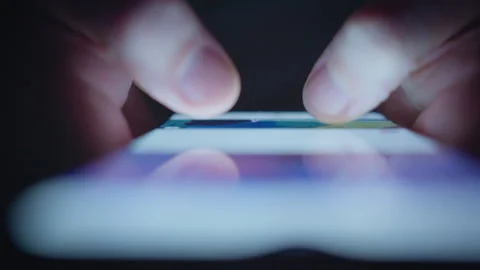 A man is looking at images on his smartphone at night, close-up of his hands Video stock 334835189