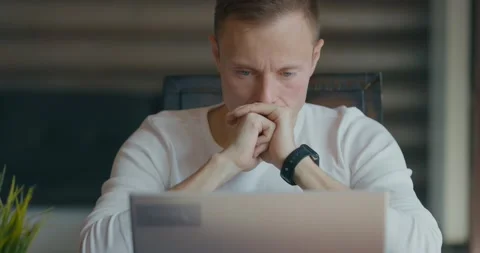 Man is looking intently at the laptop screen while sitting at his desk in the Stock Footage 197603533