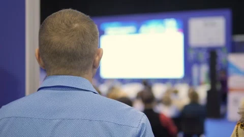 Man is looking at a large screen in a room full of people Stock Footage 298943755