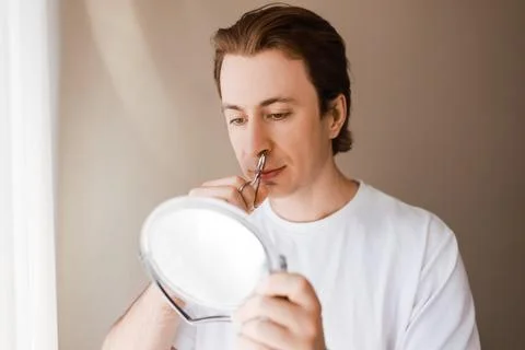 Man looking in a mirror during his male grooming routine, using scissors fo.. Stock Photos