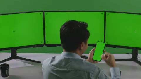 Man Looking At Mobile Green Screen Celebrating Working Multiple Computer Monitor Stock Footage 249633839