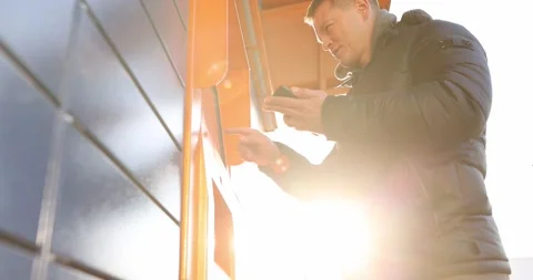 Man looking into mobile phone and dialing code on keypad of postal machine 4k Stock Footage 170295149