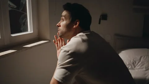 Man looking night window bedroom feeling depression closeup. Worried guy on bed Stock Footage 278289473