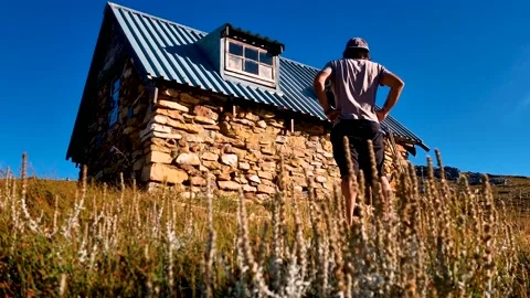 Man Looking at old mountain stone house 動画素材 195945526