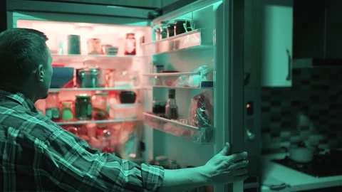 Man looking into open refrigerator at night in dark kitchen. Concept of mid.. Video stock 332054999