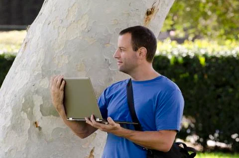 Man looking out while holding a lap top outside. Stock Photos