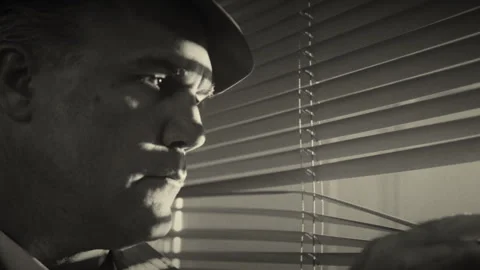 Man looking out of window blinds in black and white Stock Footage 275641927