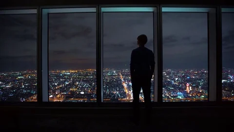 Man looking out a window high above the city Stock Footage 83857453