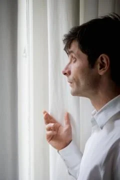 A man looking out a window Stock Photos