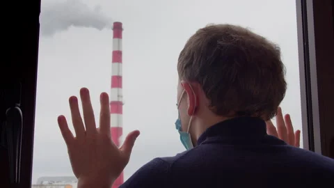 Man looking out of a window at poisonous smoke coming out of a factory chimney Stock Footage 303635203