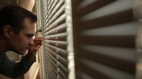Man looking out the window through the blinds to the street, spying. suspected Stock Footage 72904271