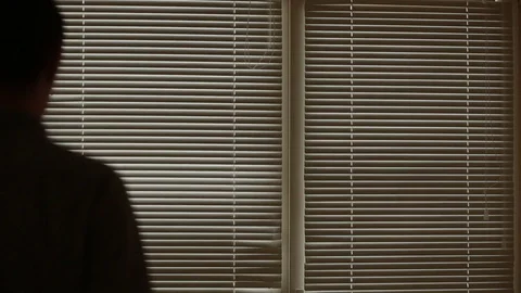 Man looking out the window through the blinds to the street, spying. suspected Stock Footage 72982755