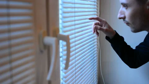 Man looking out the window through the blinds to the street, spying. suspected Stock Footage 89044717
