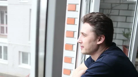 A man looking out the window while standing on the balcony Stock-Footage 60423511