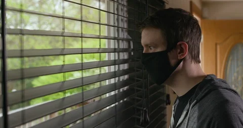 Man Looking Out Of Window While Wearing Homemade Protective Face Mask PPE Vídeo Stock 129565172