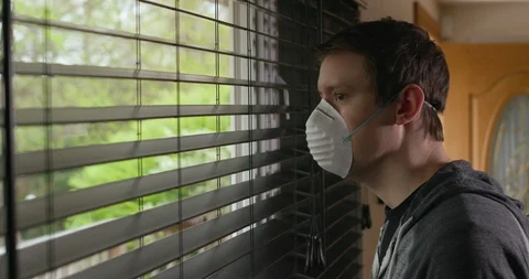 Man Looking Out Of Window While Wearing White Protective Face Mask PPE Vidéo 129565261