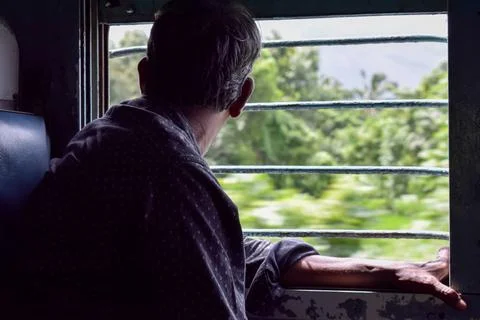 Man looking outside through train window. Stock Photos