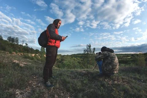 A man looking at the phone while the second photographs stones Stock Photos
