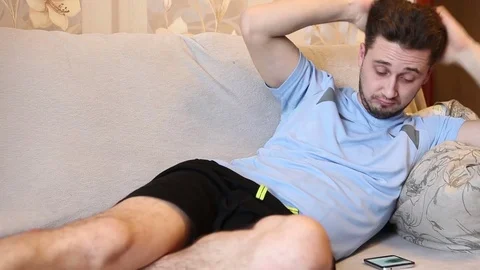 Man looking photos on the phone while lying on a sofa Stock Footage 72582080