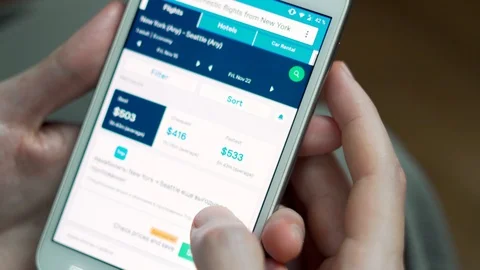A man is looking for plane tickets on the Internet online using a smartphone cel Stock Footage 119689673