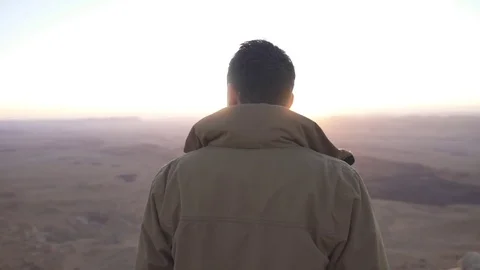 Man looking at the rising desert sun Stock Footage 73080438