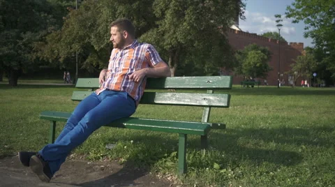 Man looking round, sitting on wood brench, pan shot 库存影片 52715744