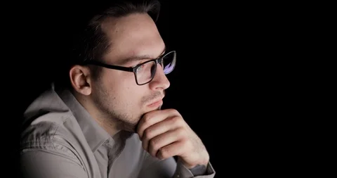 Man is looking at screen in the dark and thinking sitting in workplace. Stock Footage 105302919