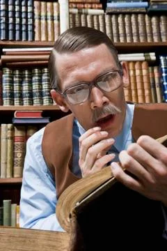A man looking shocked while reading a book in a bookstore Stock Photos