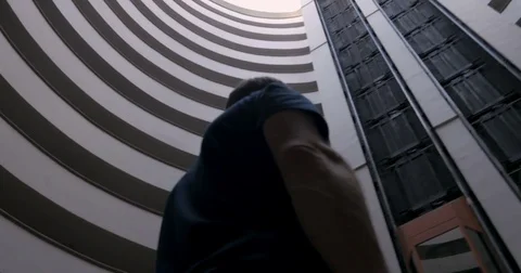 Man looking up at the sky through the center of a round building Видео 83149566