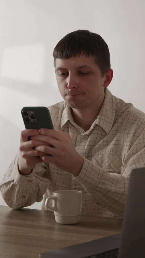 Man looking at smartphone screen while drinking coffee at table close up Stock Footage 335082387