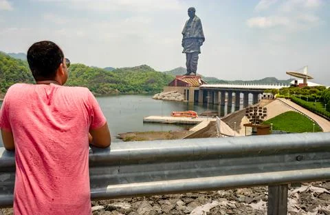 Man looking at the statue of unity with bright dramatic sky at day from diffe 写真素材