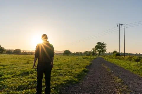 A man looking at the sunset. With sun flare. In the countryside on a spring Stock Photos